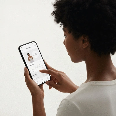 Person interacting with a wellness app on a smartphone, showing personalized health data or a meditation guide, with a clean and bright background